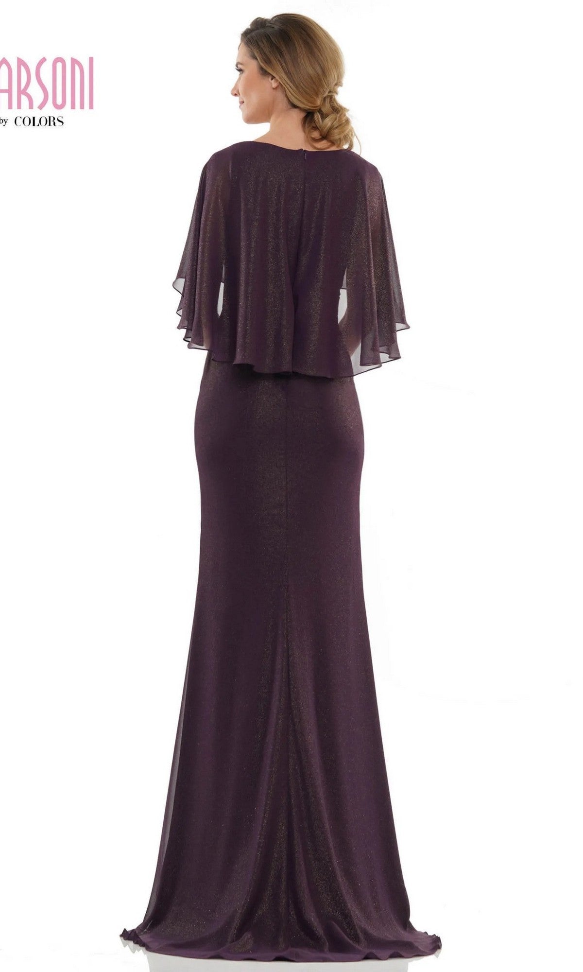 A woman wearing the Marsoni MV1130 long formal dress, a floor-length dark purple sheath gown with a sheer cape-style overlay, stands facing away from the camera.